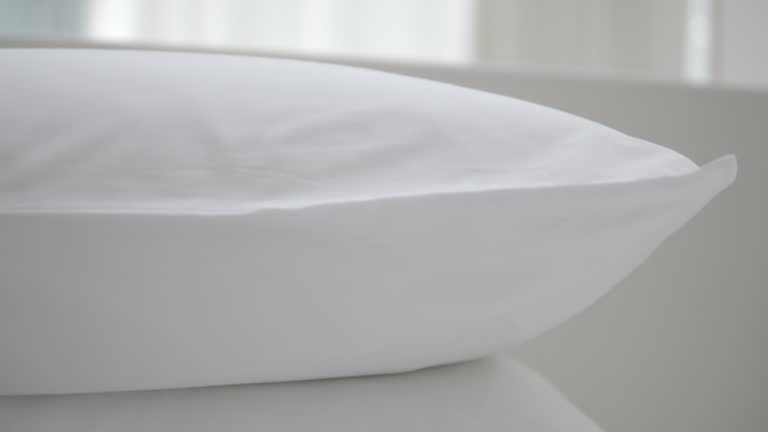 Close-up of a clean, fresh white pillow on a bed, emphasizing proper pillow washing techniques.